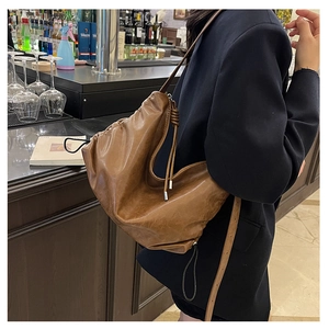 Close-up of caramel leather hobo bag with drawstring detail and lychee texture