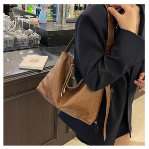 Detail of dark brown leather shoulder bag with knotted strap and silver zipper closure
