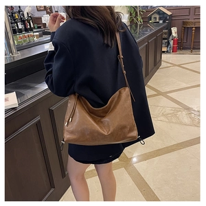 Detail of dark brown drawstring crossbody bag with soft faux leather pleats and strap