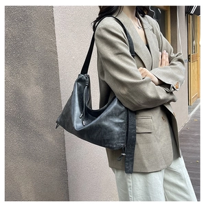 Detail of a large black oversized hobo bag with drawstring and wide shoulder strap