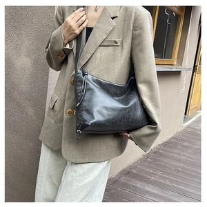 Detail of black vintage leather hobo bag featuring side drawstring and metal accents