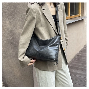 Detail of black faux leather half-moon bag featuring vintage texture and adjustable strap