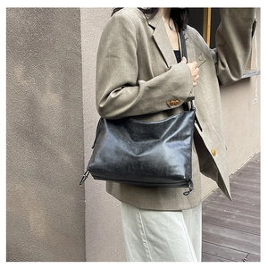 Detail view of black vintage leather tote bag with logo embossing and side drawstring
