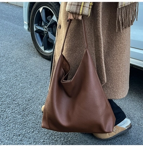 Close-up of pebble-textured brown leather tote bag showing soft drape and minimalist finish