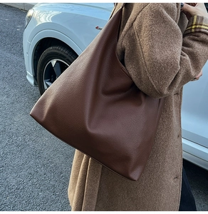 Close-up of deep brown lychee grain leather tote bag with minimalist folding detail
