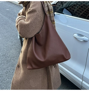 Close-up of a large vintage brown leather hobo bag worn by a model in a commute setting