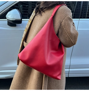 Rear view of a red leather hobo tote bag worn with a camel coat and plaid scarf