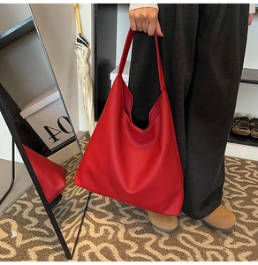Detailed view of large red tote bag with lychee grain texture and minimalist leather strap