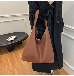 Brown lychee texture leather tote bag shown with a model in a minimalist modern interior