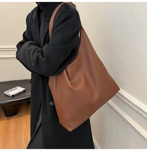 Brown lychee leather hobo bag styled on a black coat for a minimalist commuter look