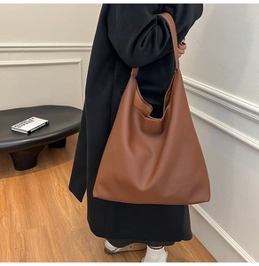 Detail of a large brown faux leather tote bag with lychee texture for office commuting