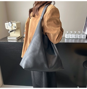 Close-up of black lychee grain leather tote bag showing spacious capacity on model