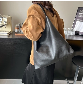 Detailed side view of a black pebbled leather large hobo shoulder bag on a model
