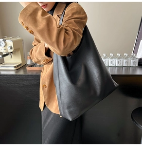 Side view of large black lychee texture tote bag on model in casual office setting