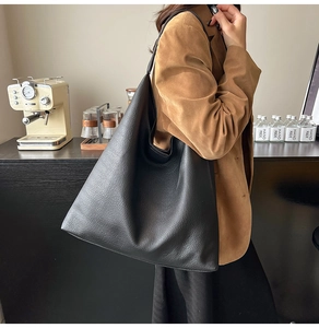 Detail of black lychee grain leather tote bag worn as a shoulder bag in a cafe setting