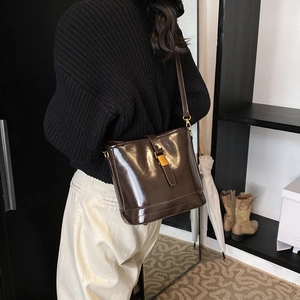 Sac seau vintage marron foncé en cuir brillant avec boucle dorée et bandoulière réglable
