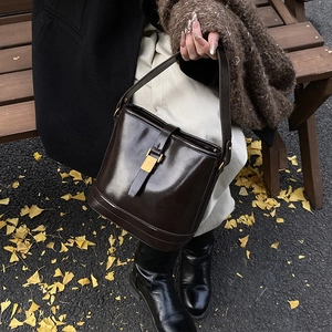 Sac seau vintage en cuir marron chocolat avec boucle dorée dans un décor de rue automnal