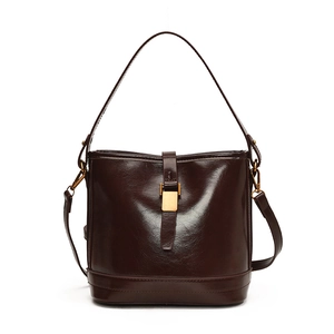 Sac seau en cuir chocolat brillant avec poignée et fermoir doré sur fond blanc