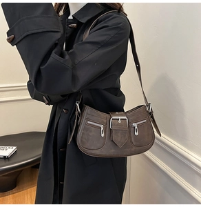 Detail of vintage brown shoulder bag with silver zippers and buckle on black coat