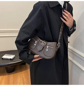 Close-up of retro dark brown shoulder bag featuring functional zippers and adjustable strap