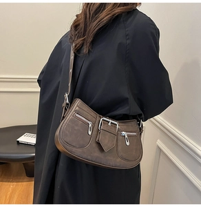 Detail of vintage brown shoulder bag featuring dual zipper pockets and matte leather texture