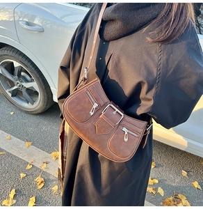 Detailansicht der braunen Lederhandtasche mit Metallreißverschlüssen und großer Schnalle