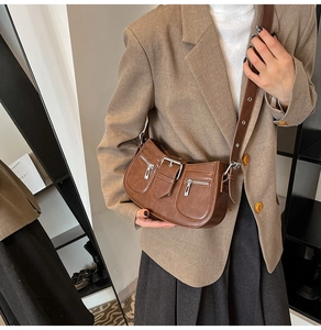 Close-up of brown vintage shoulder bag with metal zipper and buckle on a suit jacket