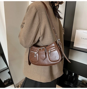 Detail of dark brown retro baguette bag with dual zippers and adjustable shoulder strap
