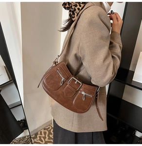 Detail view of dark brown vintage underarm bag with silver zippers and buckle on shoulder strap