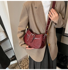 Detail of dark burgundy retro shoulder bag featuring metallic buckles and side zipper pockets