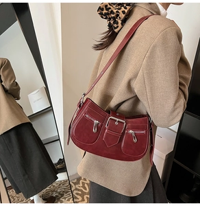 Detail view of burgundy vintage shoulder bag with metal buckle and zipper pockets