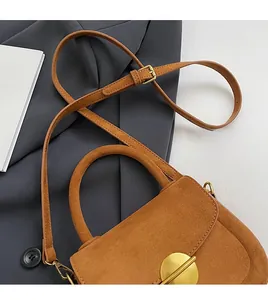 Detail of vintage warm brown suede handbag with gold circular buckle and stitching