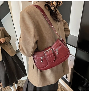 Dark red retro underarm bag with silver buckle worn over a brown blazer by a model