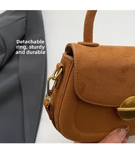 Detail of the brown matte saddle bag with gold-tone metal D-rings and detachable straps