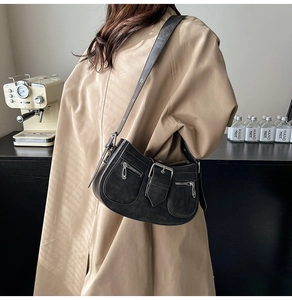 Detail view of black vintage messenger bag with silver hardware on a khaki trench coat