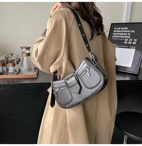 Close-up of retro black multi-pocket shoulder bag with silver hardware and utility details