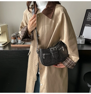 Detail einer schwarzen Halbmond-Schultertasche mit Retro-Schnallen und Metallzippern