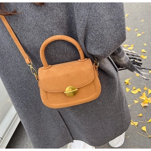 Detail of vintage brown suede saddle bag with golden circular buckle and leather strap