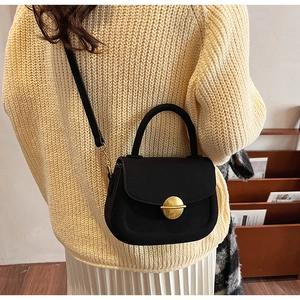 Detail of vintage black saddle bag with gold buckle on model in beige sweater