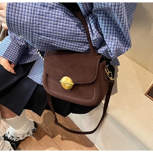 Detail of vintage dark brown suede crossbody bag with elegant golden round buckle