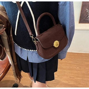 Close-up of retro dark brown saddle bag with golden metal buckle on a vintage outfit
