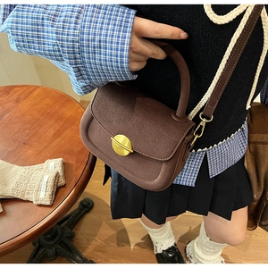 Detailed macro of coffee brown suede crossbody bag with gold metal buckle and leather strap
