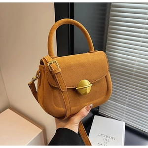 Detail view of ginger yellow saddle bag with matte leather and golden metal buckle