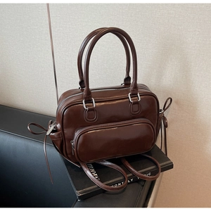 Detailed view of the brown leather bowling bag with side bow and front zipper pocket