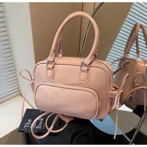 Detalle del bolso Boston rosa con lazos de cinta y bolsillo frontal en superficie de espejo