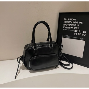 Detail view of black vintage leather handbag with wide front zip pocket and silk ribbon