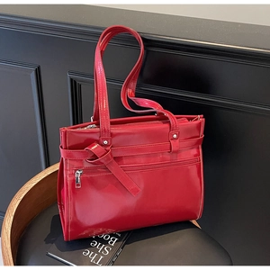Détail du nœud élégant et de la finition en similicuir rouge brillant sur ce grand sac