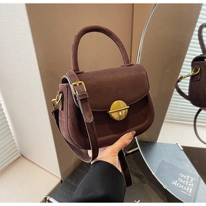 Detailed mirror reflection of brown suede handbag with golden metal round buckle