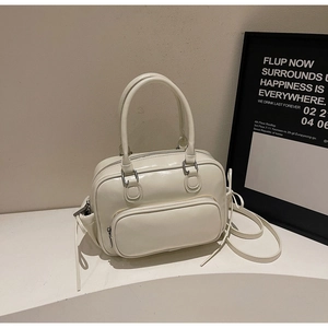 Detalle de bolso tote beige con asas dobles y correa de hombro ajustable en una mesa