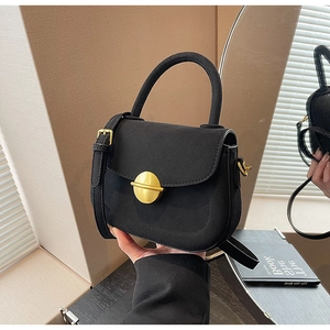 Close-up of black suede crossbody bag with premium gold round metal buckle detail